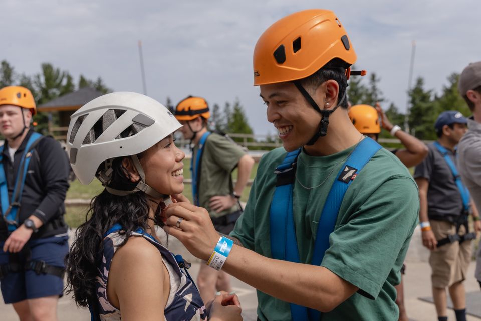 A man helps his girlfriend tighten the straps on her helmet as they prepare for ziplining at the Blue Mountain Resort Adventure Park Base Camp.