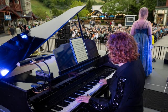 A pianist performing live behind classical vocalists on the Subaru Stage, with views of the mountain in the backdrop
