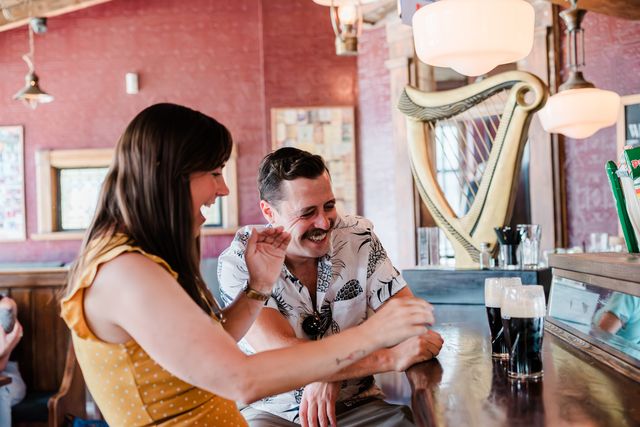 A couple laughing at the bar while sipping on a couple pints of cold Guiness at MJ Byrne's Irish Pub in the heart of Blue Mountain Village.